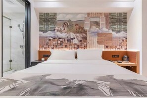 A bedroom with a large bed, a wooden headboard, a nightstand, and a wall-mounted shelf.