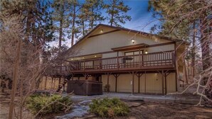 A two-story lodge with a balcony, a hot tub, and a small stream in the foreground. - The Bear Slumbers in Big Bear, spa, WiFi, foosball, pool/ping-pong (Big Bear)