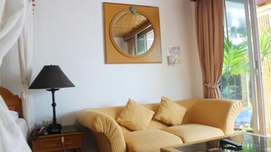 Une pièce comprenant un canapé, une lampe, un miroir et une fenêtre avec des rideaux.