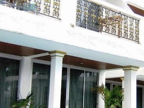 A building with a balcony featuring ornate metal railings and a white facade.