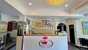Un comptoir d’accueil orné d’un logo, un lustre, des tableaux encadrés et une horloge murale.