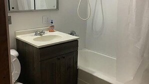 Ein Badezimmer mit einem weißen Waschbecken, einem dunklen Holzschrank und einer weißen Toilette.
