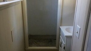 Ein kleines, schmales Badezimmer mit Dusche, Waschbecken und Toilette.