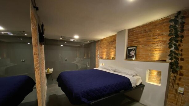 Une chambre à coucher moderne avec un lit, un miroir et un mur en briques.