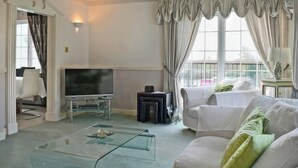 Un saló amb televisió de pantalla plana, taula de cafè de vidre, sofàs blancs i un penjoll.