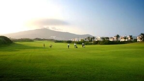 A golf course with a mountain in the background and a row of houses on the right. - Apartment with pool view at La Cassia 4187 complex (Cabo Negro)