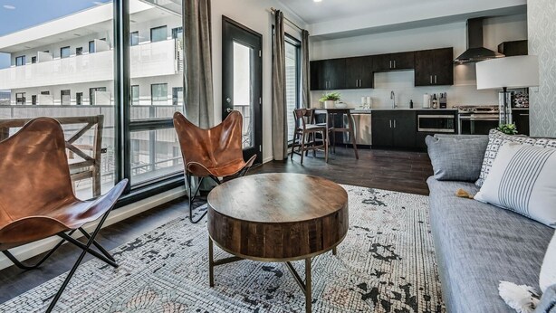Eine moderne Wohnung mit Essbereich, Küche und einem Balkon mit großen Fenstern.