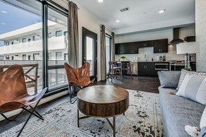 A modern apartment with a dining area, kitchen, and a balcony with large windows. - Nashville Condo Gulch/Downtown-Walking Distance! (Nashville)