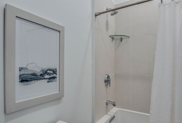 A bathroom with a framed artwork, a glass shower enclosure, and a bathtub. - Nashville Condo Gulch/Downtown-Walking Distance! (Nashville)