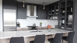Una cucina moderna con una grande isola, sgabelli da bar e mobili contenitori a incasso.