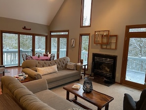 Relax in this inviting living room with a high ceiling, large windows, and a cozy fireplace.