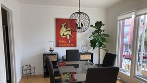 A dining area with a glass table, black chairs, a red poster, and a hanging light fixture. - Beautiful Marina Home - 2Bed 2Bath - 1 block from Marina Blvd! (San Francisco)