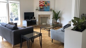 A living room with a sofa, a coffee table, a TV, a fireplace, and a painting. - Beautiful Marina Home - 2Bed 2Bath - 1 block from Marina Blvd! (San Francisco)