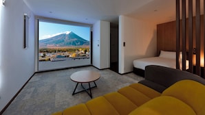 Une chambre d’hôtel moderne dotée d’une grande fenêtre donnant sur un paysage montagneux et sur la ville.
