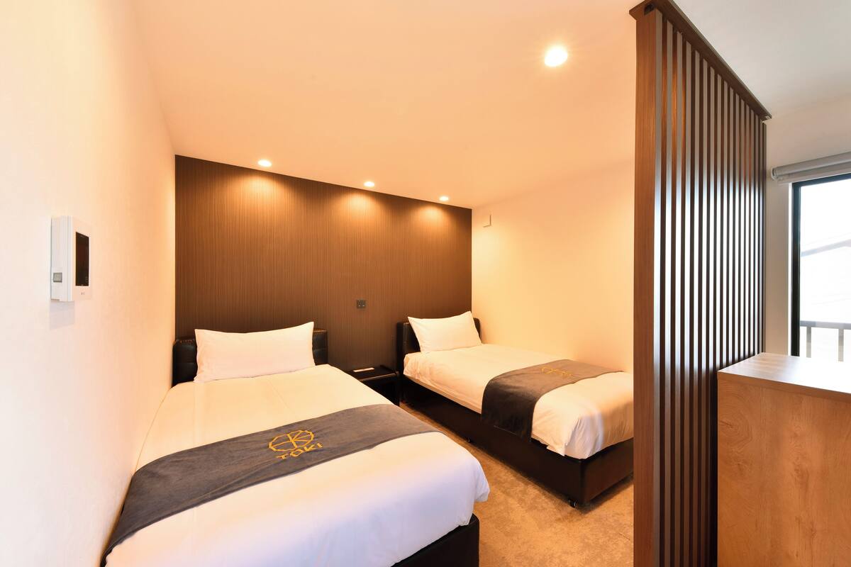 A hotel room with two beds, a wooden headboard, and a large window.