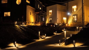 Une vue nocturne d’un quartier résidentiel, avec des bâtiments illuminés et un chemin bien éclairé.