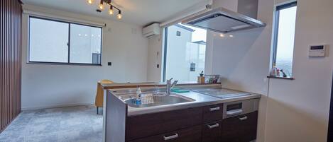 A modern kitchen with a double sink, dark cabinetry, and a built-in oven.