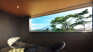 Une chambre moderne avec une grande fenêtre, deux fauteuils et une vue sur une montagne.