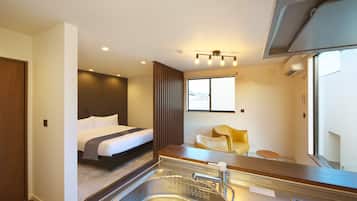 A modern hotel room with a bed, a small dining area, a sink, and a window with a view.
