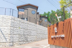 Un muro de piedra y una cerca de madera con un letrero.