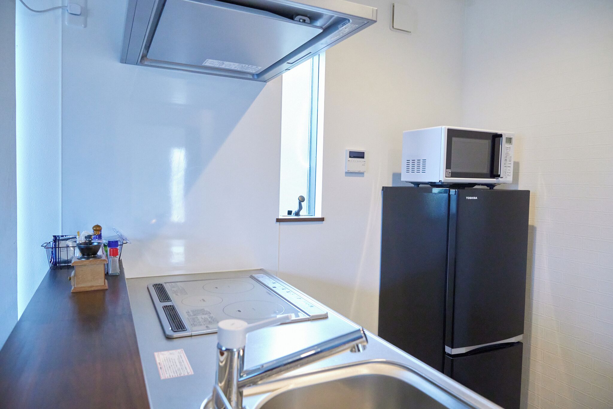 A compact kitchen with a built-in microwave on top of a refrigerator, a stove, and a sink.