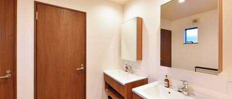 A modern bathroom with two sinks, wooden cabinets, and a large mirror.