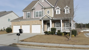 A two-story house with a front porch, garage, and a well-maintained lawn.