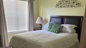 A bedroom with a bed, a lamp, a decorative wall piece, and a window with curtains. - 2 bed, 2 bath condo close to Disney and other theme parks Orlando (Kissimmee)