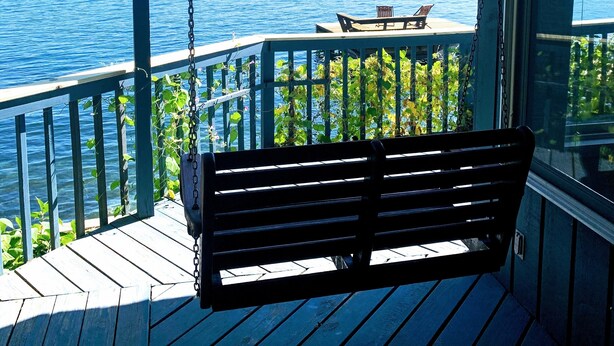 A wooden deck with a bench, overlooking a body of water and distant land. - Lakeside Life on Keuka's Water's Edge (Hammondsport)