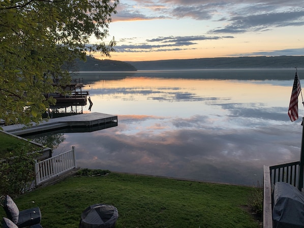 A lakeside view with a dock, a flag, and a grassy area.