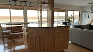 A kitchen with wooden cabinets, a countertop, and a view of the outdoors. - Lakeside Life on Keuka's Water's Edge (Hammondsport)