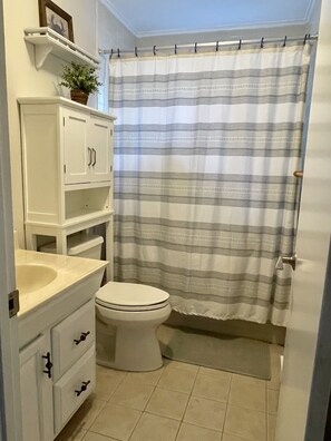 Ein Badezimmer mit Toilette, Waschbecken, Schrank und Duschvorhang.