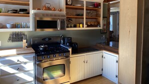 A kitchen with a stove, oven, microwave, and various utensils.