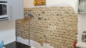 A kitchen with a stone wall, a microwave, a toaster, and a fire extinguisher.