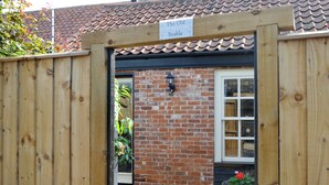 A wooden gate leading to a brick building with a tiled roof.