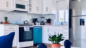 Una cocina moderna con armarios blancos, estufa, lavavajillas y refrigerador.