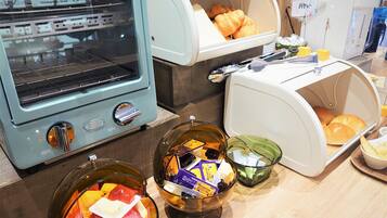 A kitchen area with a toaster oven, a bread display, and bowls containing condiments.