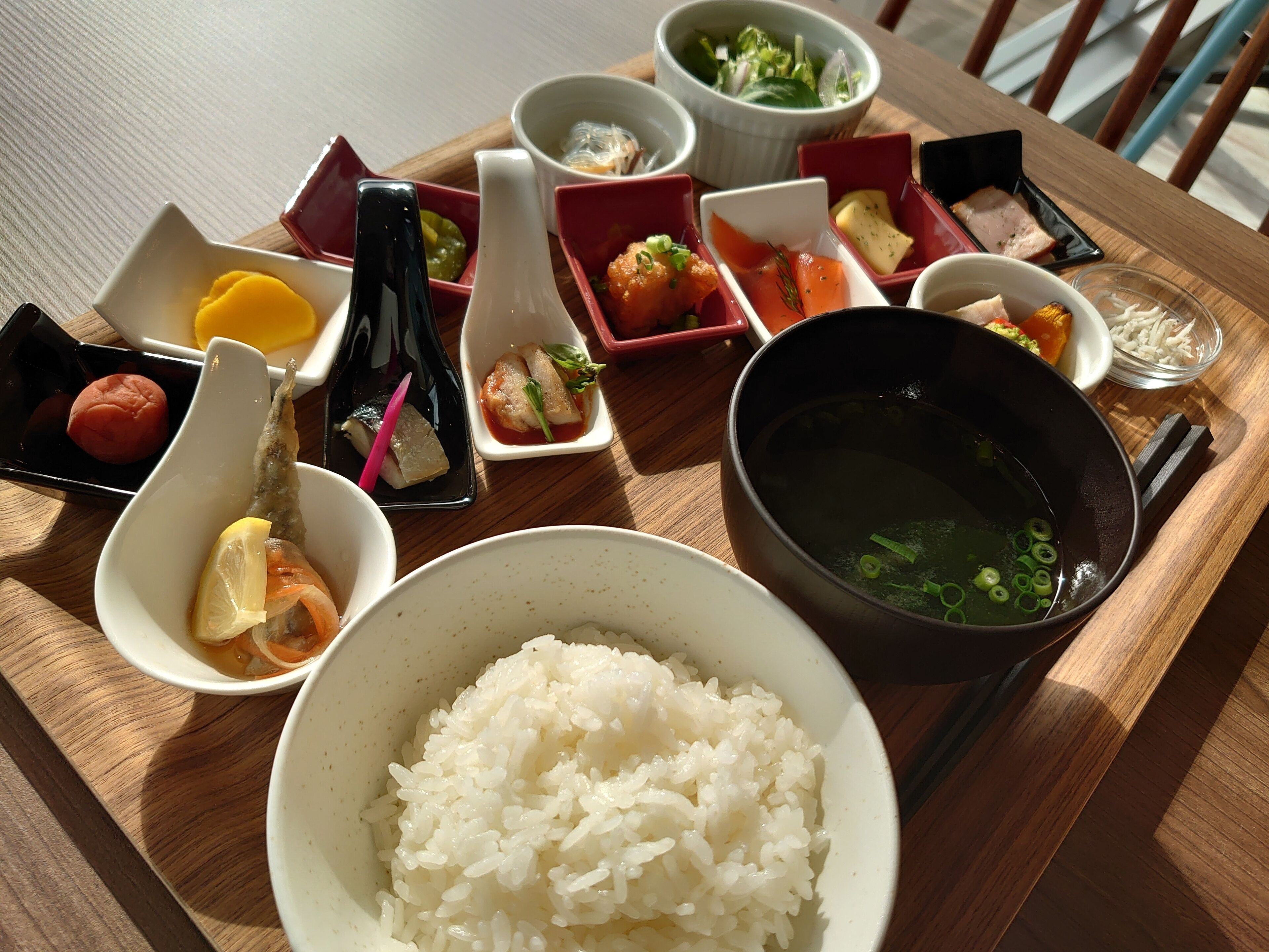 Una mesa de madera con diversos platos, incluyendo arroz, sopa y pequeñas porciones de comida.