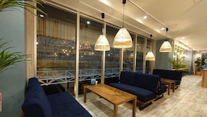 A modern interior with blue sofas, wooden tables, and hanging wicker lamps. - Green Rich Hotel Miyazakitachibanadori 2 Artificial Hot Spring Futamata Yunohana (Miyazaki)