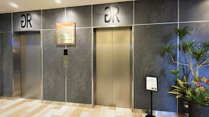 An elevator area with two elevators, a digital display, and a sign indicating 'KEEP DISTANCE'. - Green Rich Hotel Miyazakitachibanadori 2 Artificial Hot Spring Futamata Yunohana (Miyazaki)
