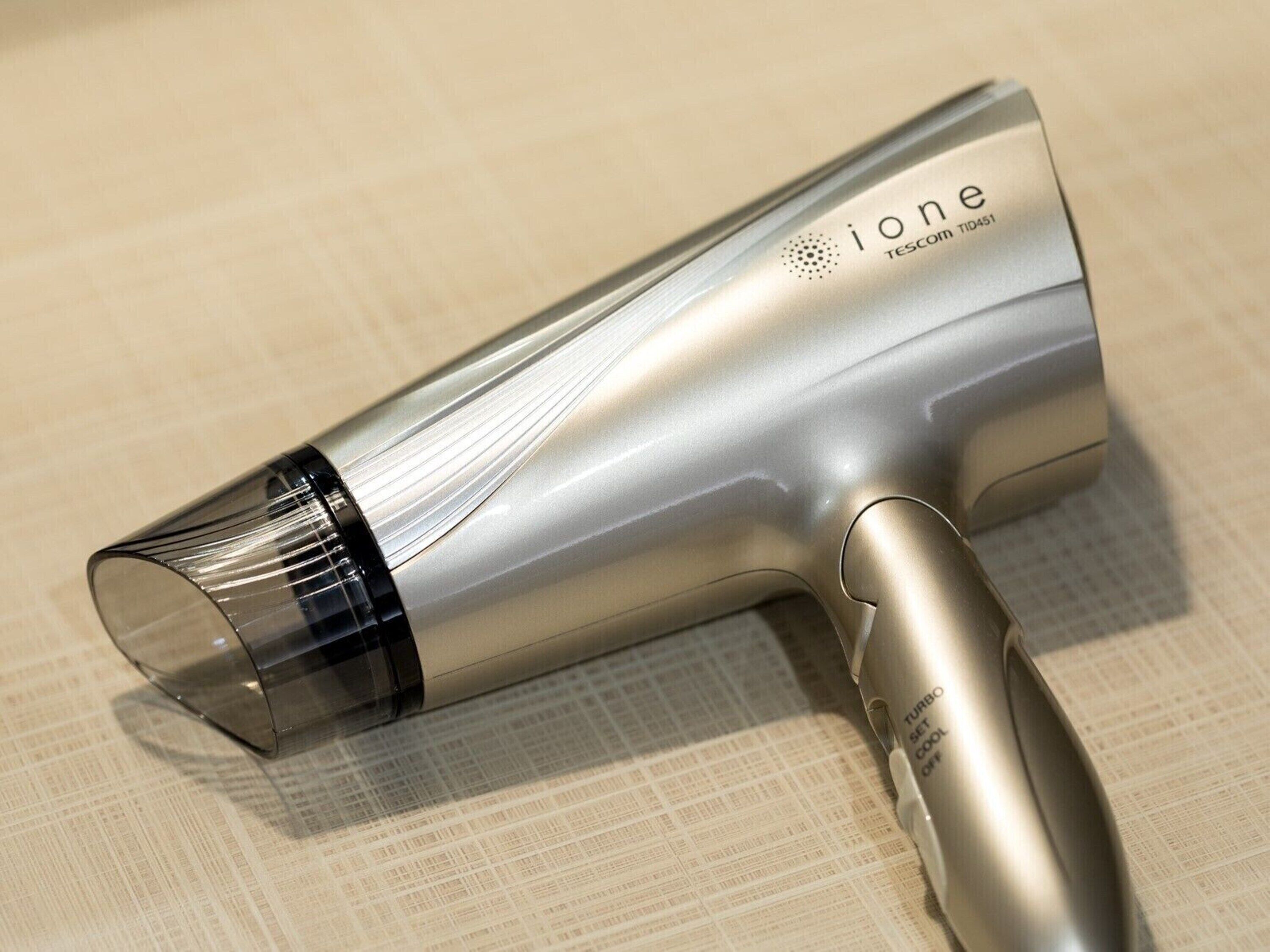 A silver hairdryer with a transparent nozzle, labeled 'ione' and 'TESCOM TID451'.