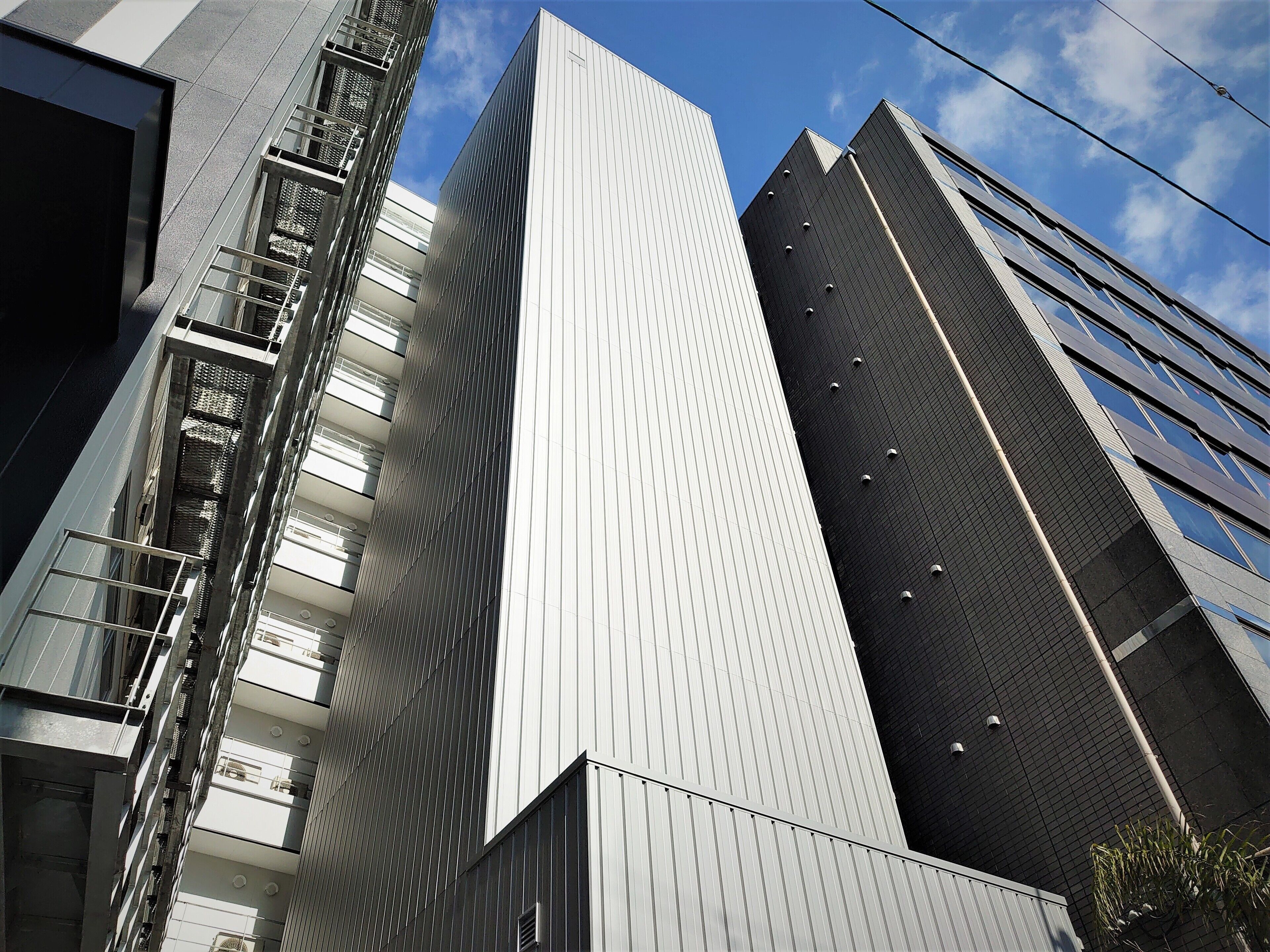 A modern high-rise building with a prominent vertical design, featuring a series of balconies and a patterned facade.