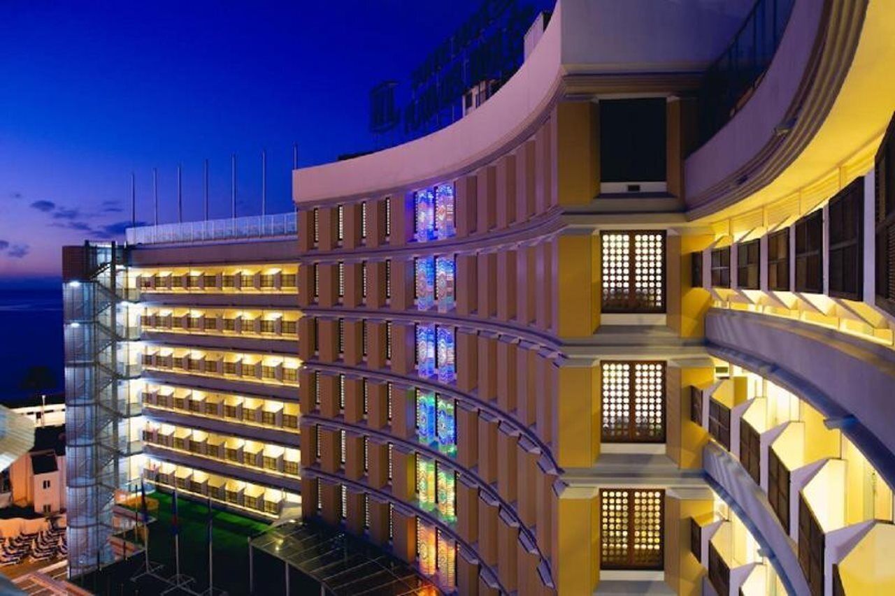 A multi-story hotel with balconies, a curved facade, and illuminated windows.
