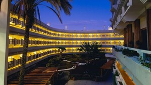A multi-story hotel with a curved facade, outdoor seating areas, and a central courtyard. - Hotel Lopez - Suitehotel Playa del Ingles (San Bartolomé de Tirajana)