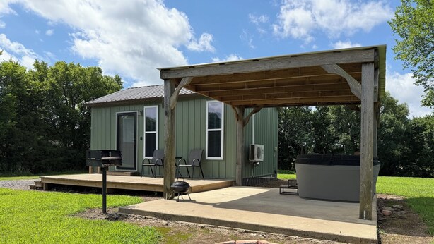 Un espace extérieur abrité comprenant un foyer, des sièges et un jacuzzi.