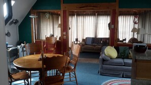 Una sala acogedora con una mesa de comedor, sillas, un sofá y una ventana con cortinas.