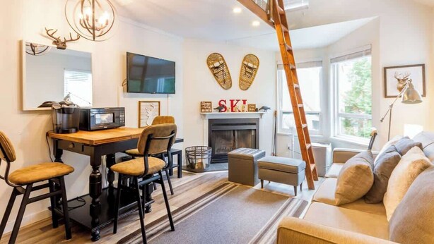 A modern living room with a fireplace, a television, and a dining area with chairs.