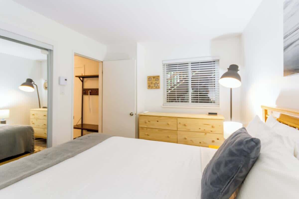 Un dormitorio con cama, mesita de noche, lámpara, cómoda y una ventana con persianas.