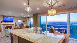 A modern kitchen with a large island, a flat-screen TV, and a view of the ocean. - 55' Ocean Front * Exclusive Ground Level Patio * A/C (San Diego)