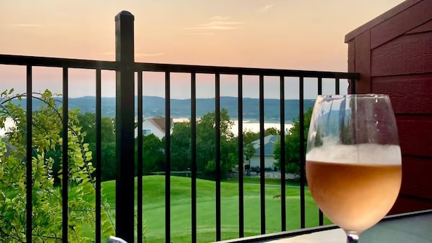 A balcony with a glass of white wine and a bowl of salad. - Lake Travis Views, King Bed, Two Sunset Decks on the Golf Course (Point Venture)